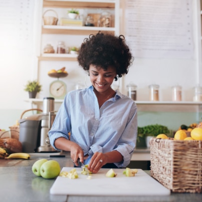 Woman in kitchen chopping fruit on a cutting board