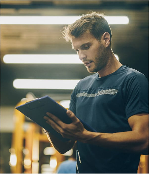 A personal trainer in a gym looks at his clipboard